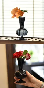 Detail of minimalist grey glass vase with fresh roses on shelf and held by hand