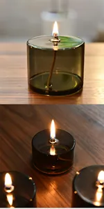 Detailaufnahme einer kreativen grünen Glasöllampe, die auf einem Holztisch brennt