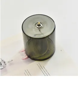 Detailansicht einer handgefertigten Öllampe aus olivgrünem Glas mit silbernem Dochthalter