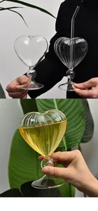 Close-up of a heart-shaped ribbed glass cup filled with yellow cocktail and a glass straw