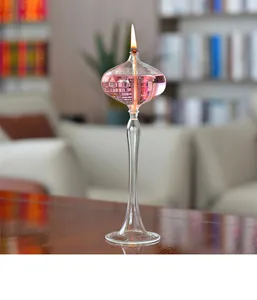 Elegant creative glass oil lamp candle holder with pink fluid lit on a modern wooden table.