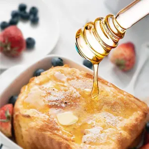 Detailaufnahme von Honig, der mit einem Glaslöffel auf French Toast geträufelt wird
