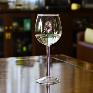 Dettaglio di una delicata rosa di vetro rosa all'interno di un calice da vino in cristallo.