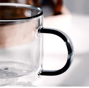 Detailed macro shot of a double-walled glass coffee cup with a sleek black handle.