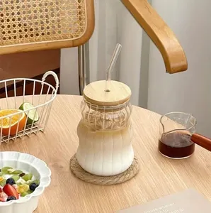 Vista detallada de la taza de vidrio estriada con tapa de bambú y pajita en escena