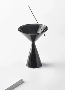 Close-up of minimalist black glass incense holder in Zen style with incense stick.