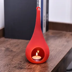 Close-up of a red teardrop-shaped glass candle holder with a lit candle inside