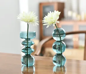 Close-up detail of blue bubble-shaped and geometric glass vases with white flowers.