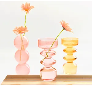 Close-up of stylish colorful bubble glass vases with fresh daisy flowers on wood