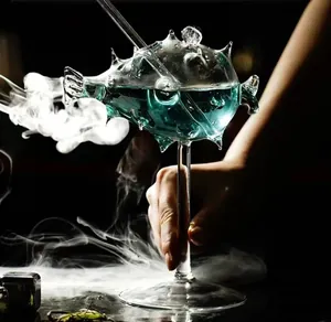 Primer plano de una copa con forma de pez globo con cóctel azul y efecto de humo