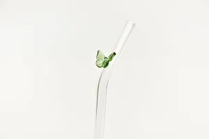 Macrodetail van het handgemaakte groene glazen vlinderornament op een glazen rietje