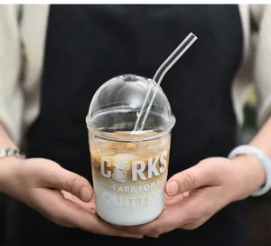 Primer plano de una elegante taza de café de vidrio en forma de U con tapa de domo y pajita