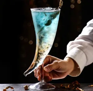 Verre à cocktail artistique en forme de corne avec liquide bleu et glace, vue main