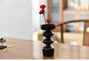 Detailed shot of a modern black glossy bubble shaped glass vase on a warm wooden table