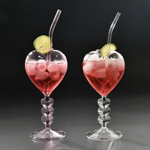 Creatieve hartvormige glazen cocktailglazen met glazen rietjes in elegante donkere setting