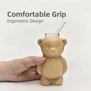 Transparent cute bear-shaped glass cup with straw for coffee or milk tea in hand