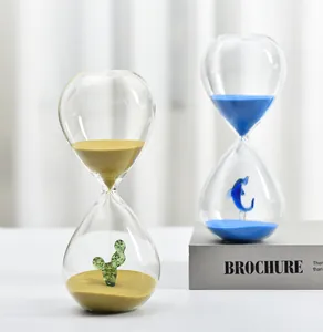Close-up of decorative glass hourglass timers featuring cactus and dolphin figurines