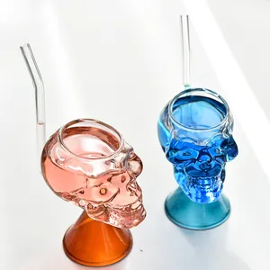 Vasos de cóctel creativos con forma de calavera y pajitas de cristal en primer plano.
