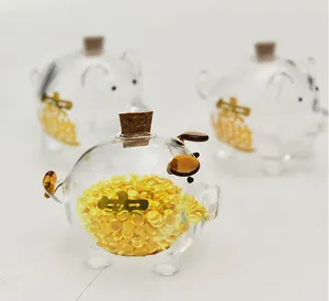 Detalle de hucha de cristal transparente con habas doradas y tapon de corcho fino