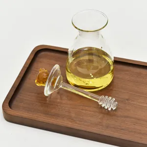 Detailansicht eines Honigglases aus Glas mit einem süßen Bären-Honiglöffel auf Holz.