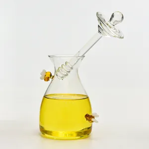 Detailansicht eines transparenten Honigglases aus Glas mit Deckel, Löffel und Bienenakzenten.