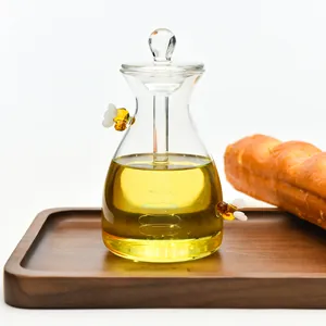 Eleganter Honigtopf aus Glas mit Bienen-Dekor, Deckel und Löffel auf Holztablett.