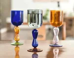 Detailed view of three elegant colorful contrast glass goblets on a wooden dining table