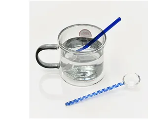 Detailansicht von blauem Glasrührstab und Löffel mit transparentem Doppelwandbecher