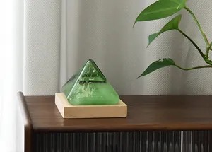 Detail view of a green glass pyramid storm glass on a wooden base in a home setting