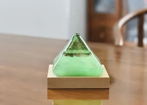 Detailed view of a green pyramid-shaped storm glass on a natural wooden base for desk decor