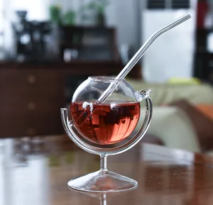 Copa de cóctel creativa con forma de globo y pajita de vidrio en una mesa de madera