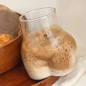 Vaso de cristal creativo con forma de glúteo para café y bebidas frías en ambiente acogedor
