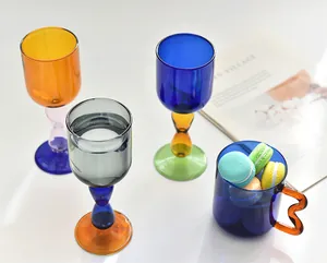 Detail of creative contrast color glass cups with macarons and a magazine on white