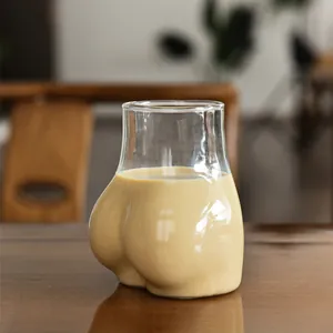 Vaso de vidrio creativo con forma de trasero para café y bebidas frías en mesa madera