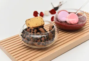 Close-up of a creative round glass dessert bowl filled with cookies on a wooden tray