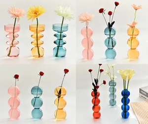 Detail showing variety of colorful geometric bubble glass vases with floral accents
