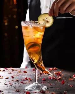 Verre à cocktail unique en forme de corne avec décoration de citron vert dans un bar.