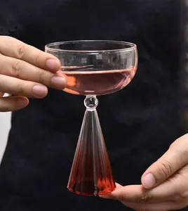 Vista detallada de una elegante copa de cóctel con un diseño único de base cónica estriada