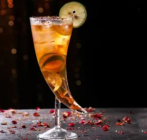 Gros plan d'un verre à cocktail en forme de corne avec garniture de citron et éclairage chaud.