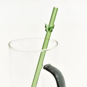 Herbruikbaar groen glazen rietje met delicaat vlinderdetail in een glazen drinkbeker