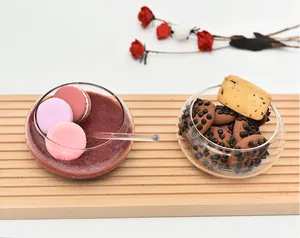 Close-up of creative glass dessert bowls filled with macarons and cookies on wood board