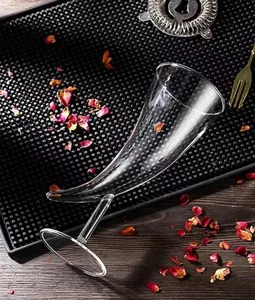 Gros plan détaillé d'un verre à cocktail unique en forme de corne sur un tapis de bar noir