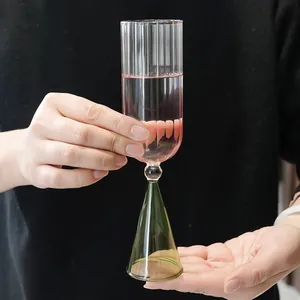 Vista detallada de un vaso de postre creativo con base cónica verde sostenido a mano