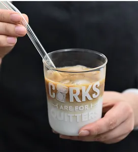 Primer plano de un vaso de vidrio minimalista en forma de U con pajita y café helado