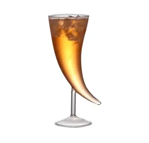 Verre à cocktail unique en forme de corne avec liquide ambré glacé sur fond blanc.