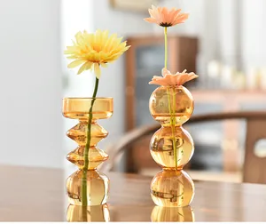 Detail view of amber bubble glass flower vases in a warm lifestyle interior setting