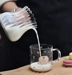 Macro view of milk pouring into a heat-resistant glass mug with floral pattern design