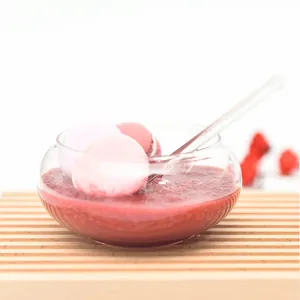 Elegant clear glass dessert bowl on a wooden board filled with pink macarons and smoothie