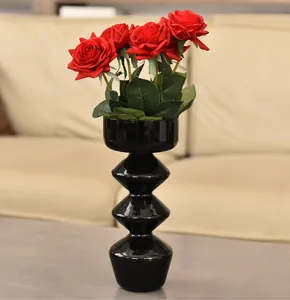 Moderno vaso di design in vetro a bolle nero con rose rosse su un tavolo neutro