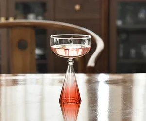 Vista de detalle de una elegante copa de postre de cristal con degradado rosa en una mesa.